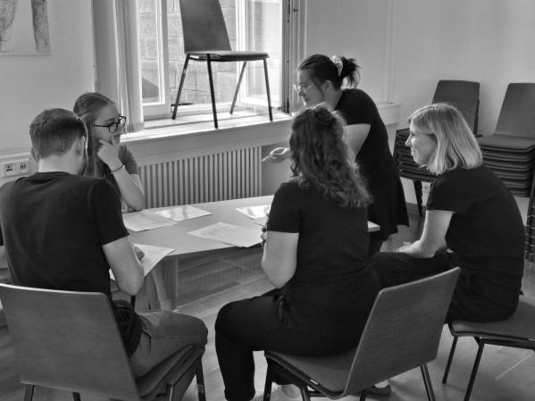 5 Azubis sitzen als Gruppe am Tisch und arbeiten
