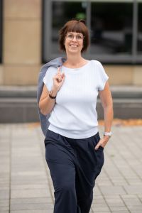 Monika Biewer geht näher auf mich zu; sie hat mich fast erreicht; Blazer locker über der Schulter