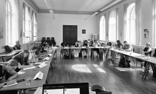 15  Azubis sitzen am Tisch und arbeiten